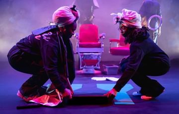 Two young people adjust a hairdressing chair on stage
