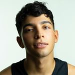 A young British-Libyan male with black hair wearing a black vest