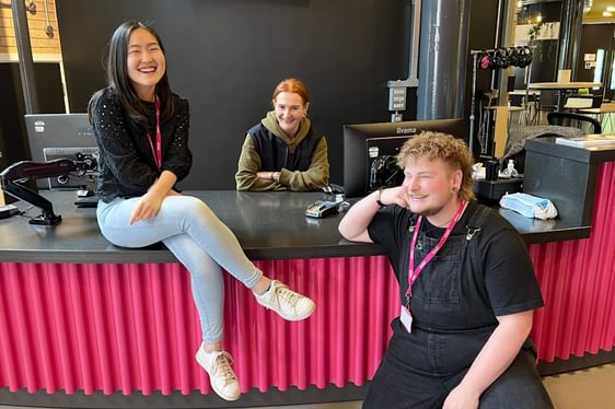 Three people sat at the Box Office, smiling.