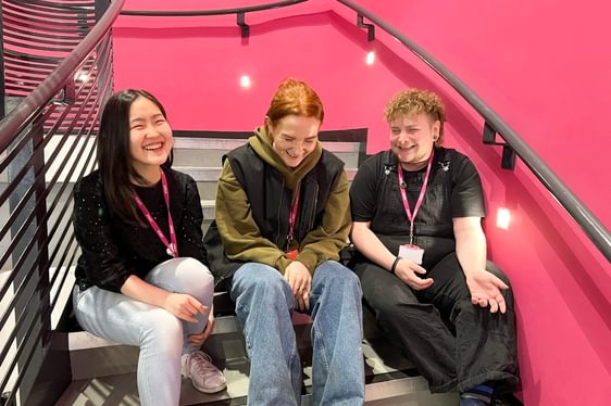 Three people sat on the staircase, smiling.