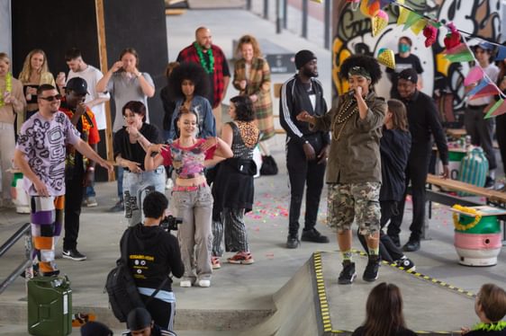 A group of young people perform a colourful show in a skatepark