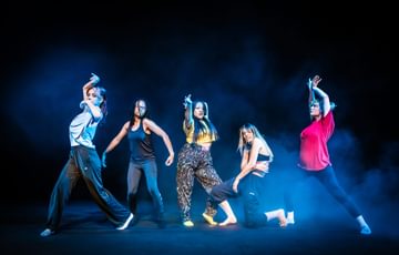 Young people dance on stage with blue haze and lights