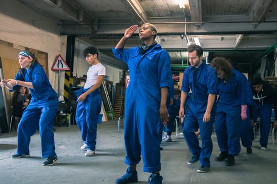 A group of people dressed in blue boiler suits performing a show