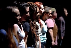 A side angle shot of the profiles of a group of young people lined up on stage