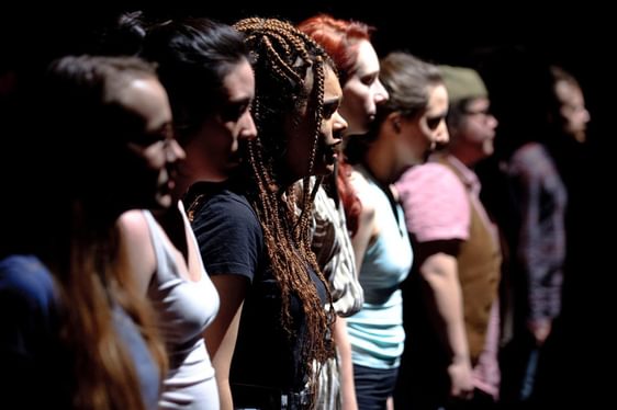 A side angle shot of the profiles of a group of young people lined up on stage