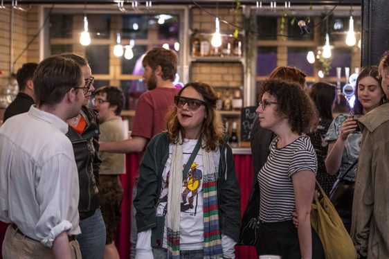 A crowd of people chatting at the bar.