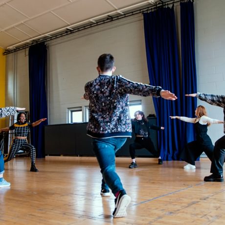 Young people hold warrior yoga poses in a rehearsal room