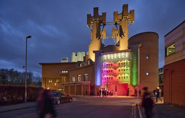 An image of the Contact building at dusk lit up in rainbow colours
