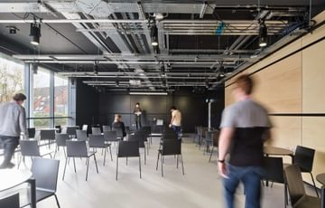 Space 0: There are some chairs set up in the space and a few people are walking around.
