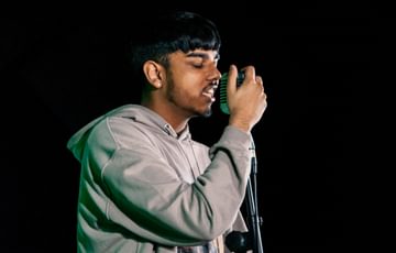 A young man sings into a microphone