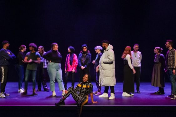 Keisha Thompson sat on the edge of the stage with members of the Contact staff team chatting behind her