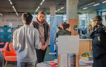 A group of people huddle chatting excitedly in a library