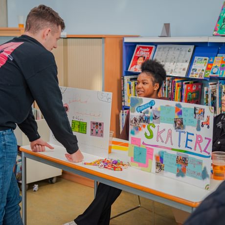 A young man leans over a display table in a library