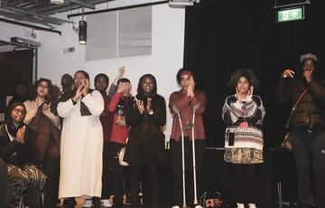 A group of young people stand in a circle in a room